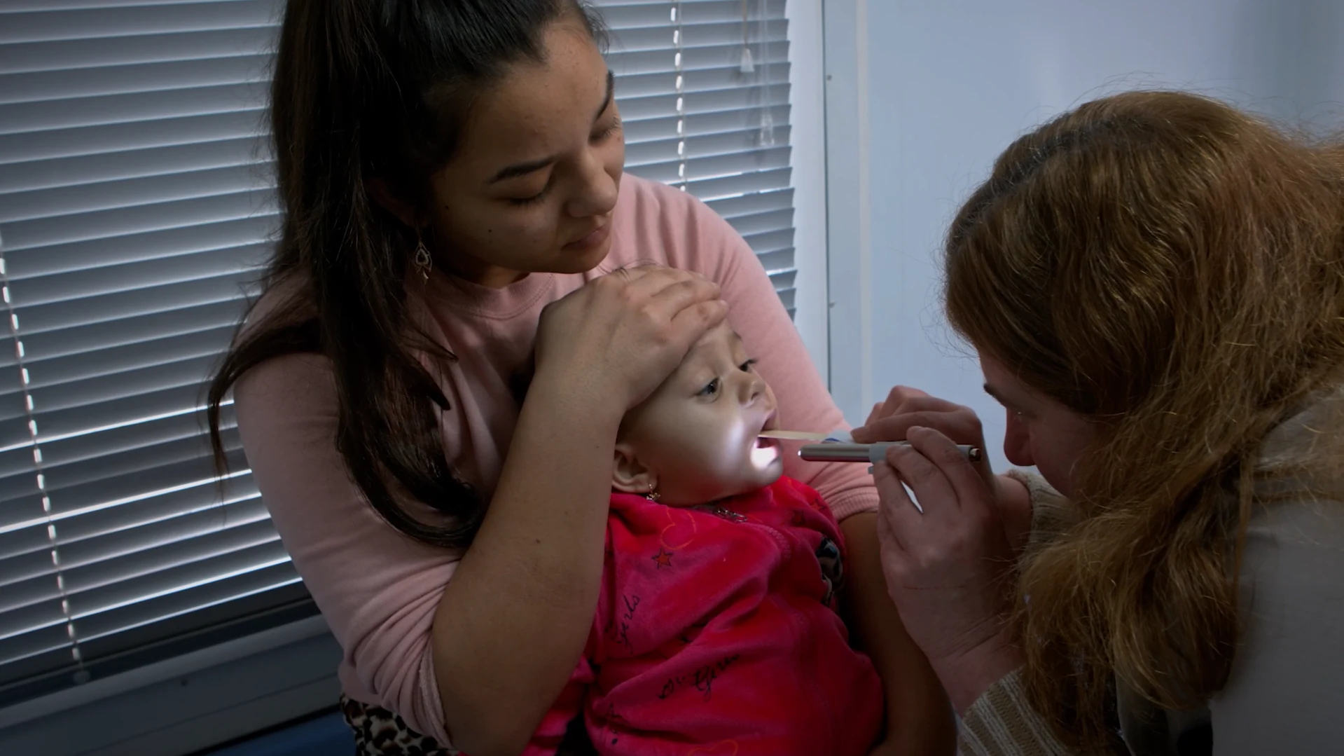 Кадр із серії UNICEF: Мама тримає дитину під час огляду медсестрою